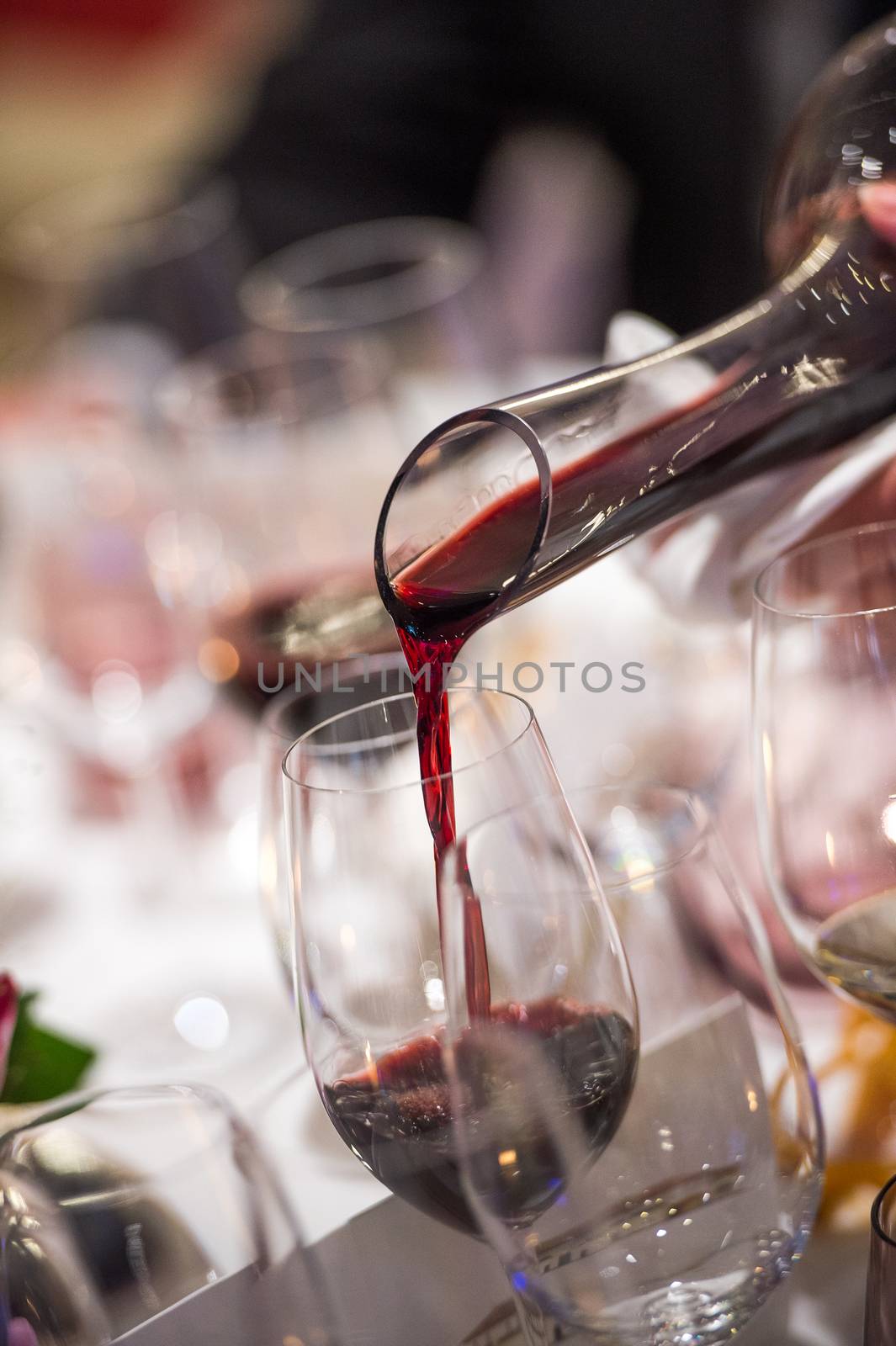 Sommelier pouring wine into glass from mixing bowl at luxury diner