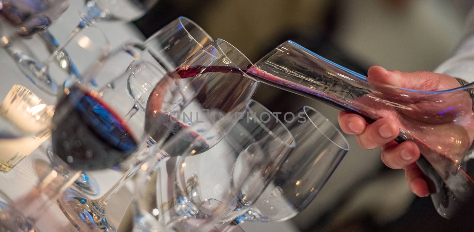 Sommelier pouring wine into glass from mixing bowl at luxury diner