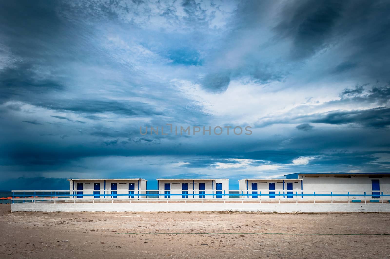 White and blue building on the beach under a dramatic cloudy day of autumn - Platamona - Sardinia - Italy