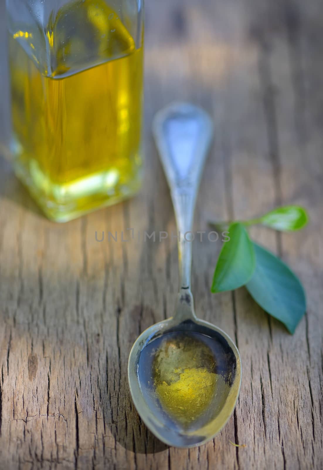 Spoon full of olive oil on wooden table