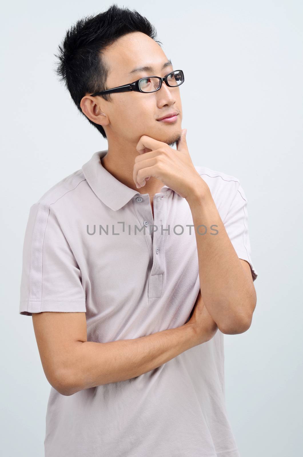 Portrait of Asian man arms crossed looking at side, standing isolated on plain background.
