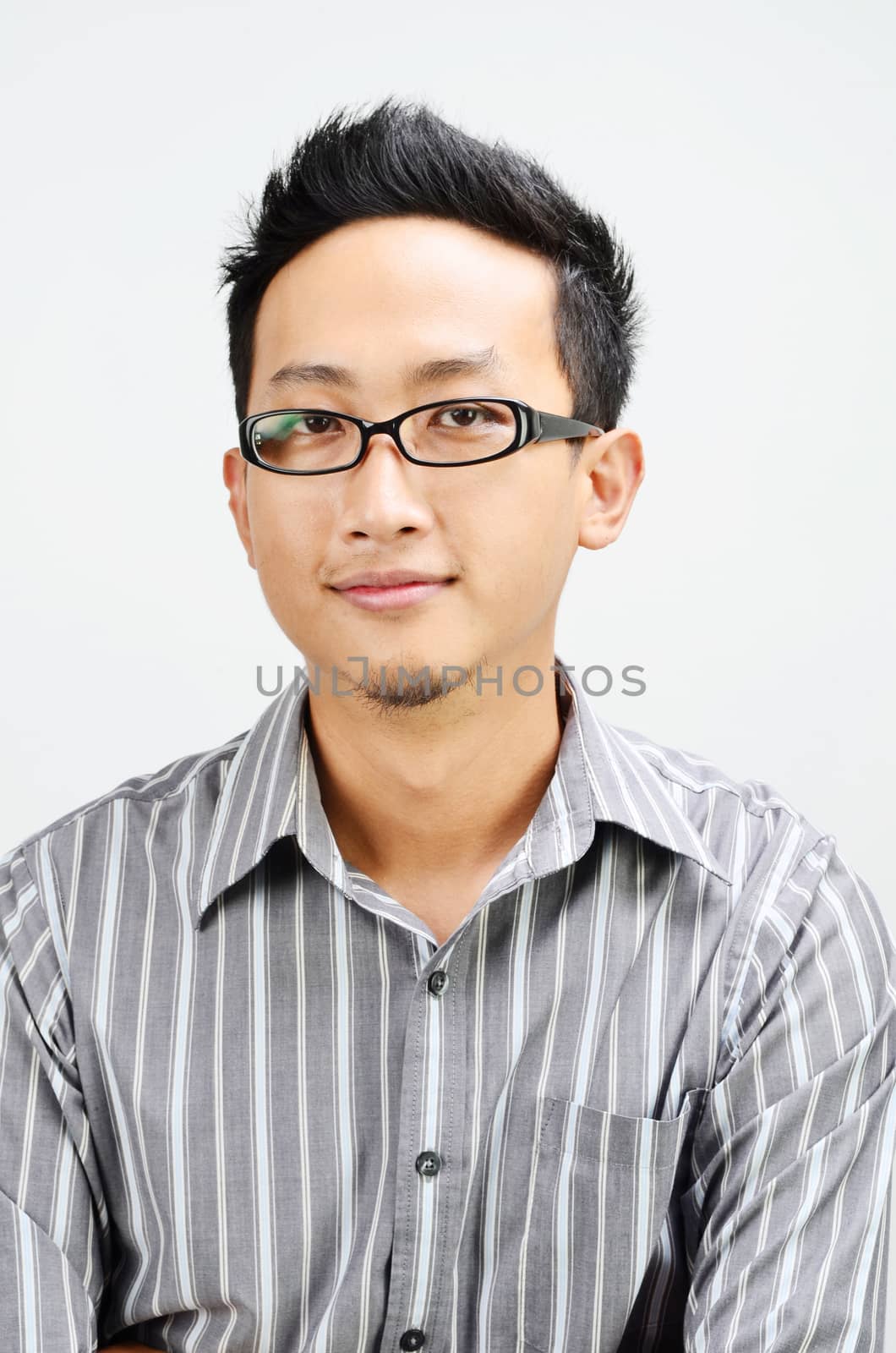 Portrait of cool Asian businessman smiling, standing isolated on plain background.
