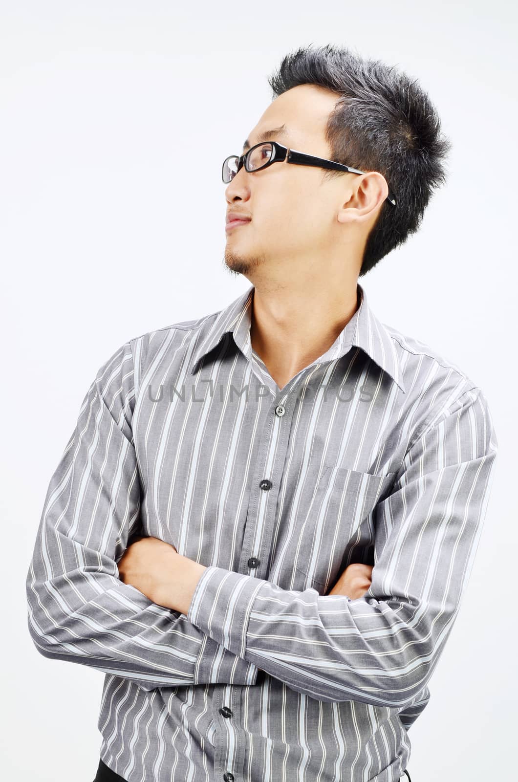 Portrait of cool Asian businessman arms crossed and looking at side, standing isolated on plain background.