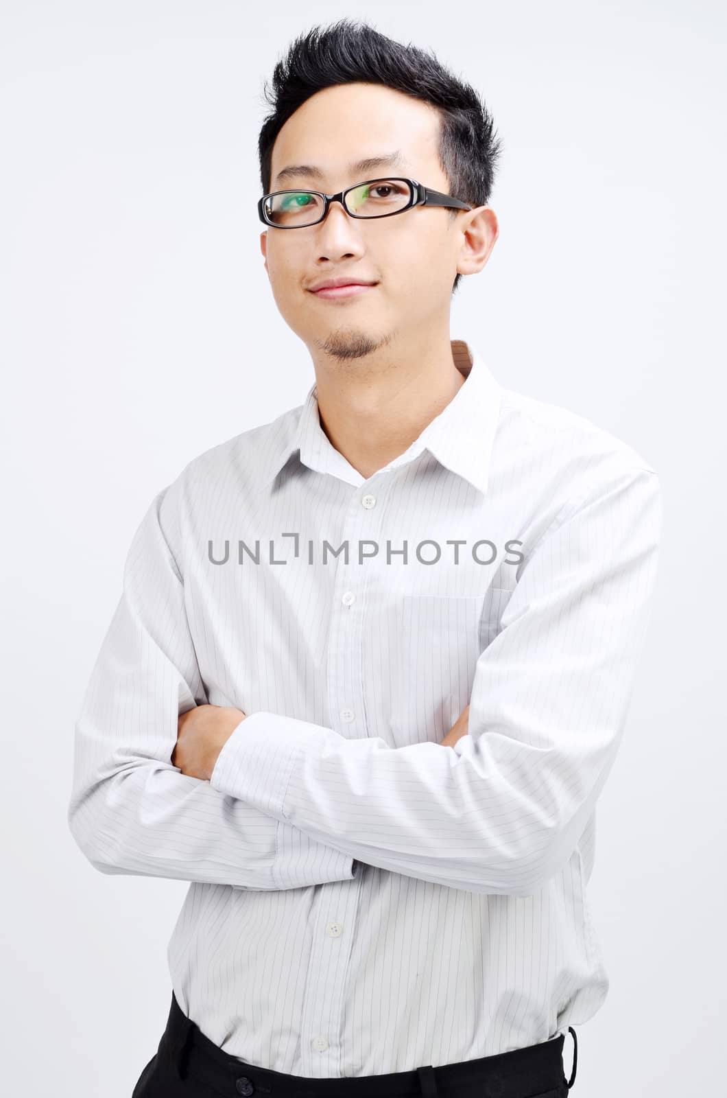 Portrait of Asian business man arms crossed and smiling, standing isolated on plain background.