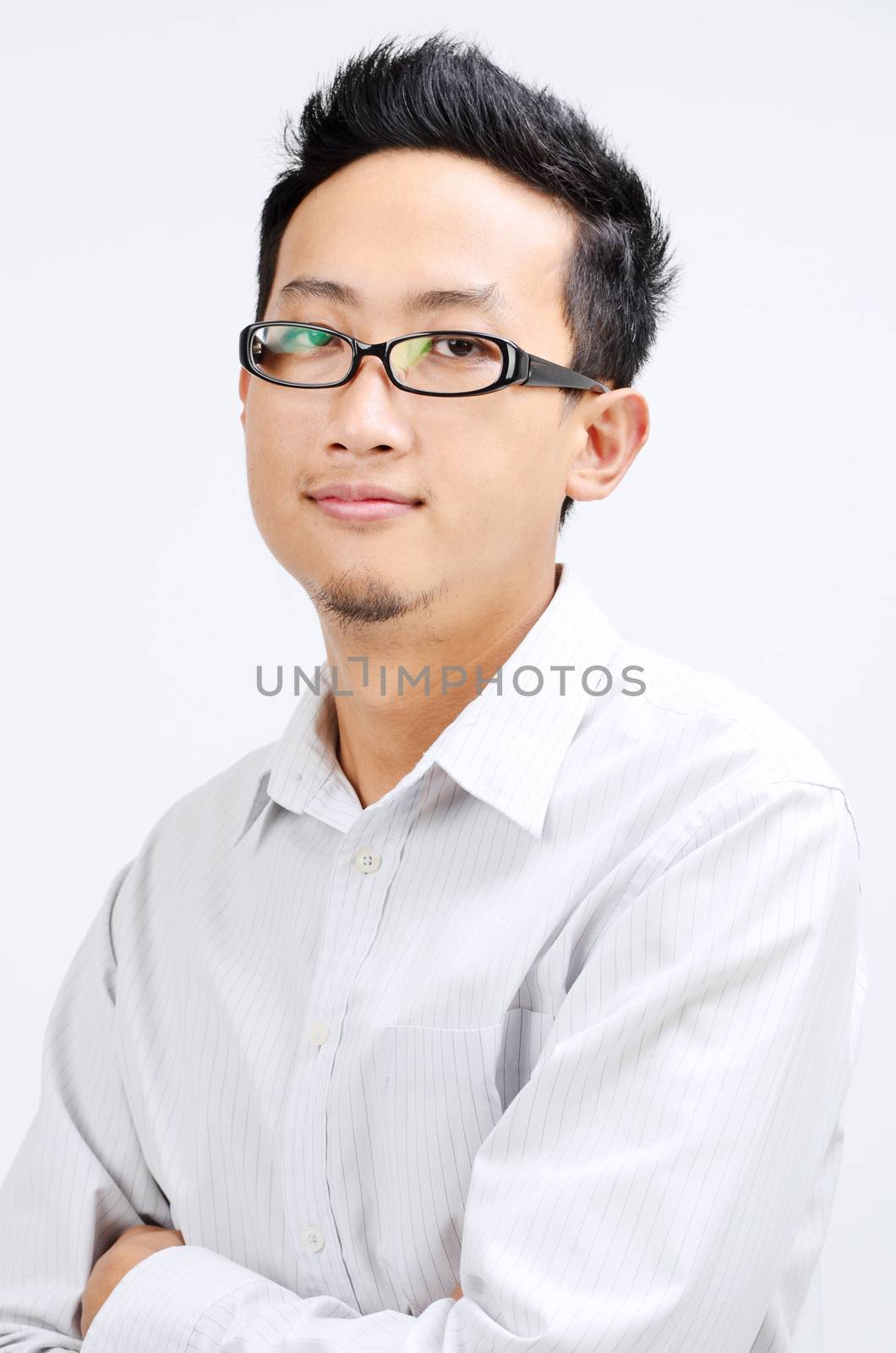 Portrait of Asian business man arms crossed, standing isolated on plain background.