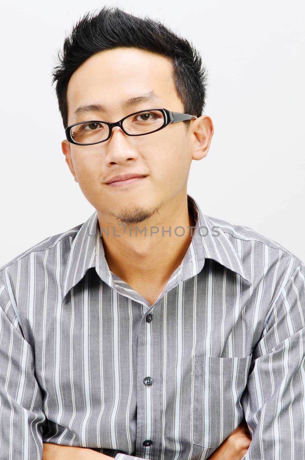 Portrait of cool Asian businessman arms crossed, standing isolated on plain background.