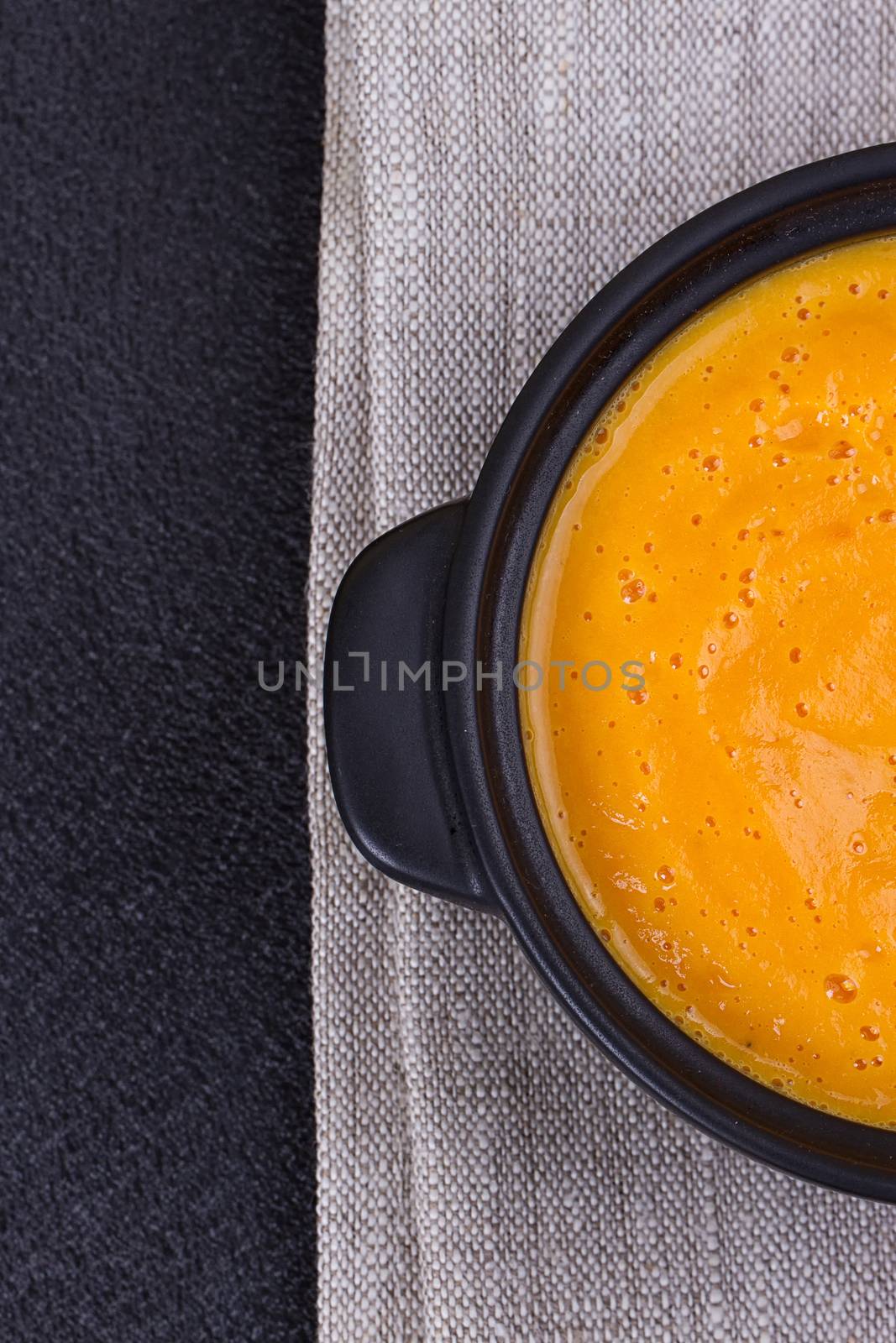 Pumpkin and carrot soup with cream and parsley on dark background