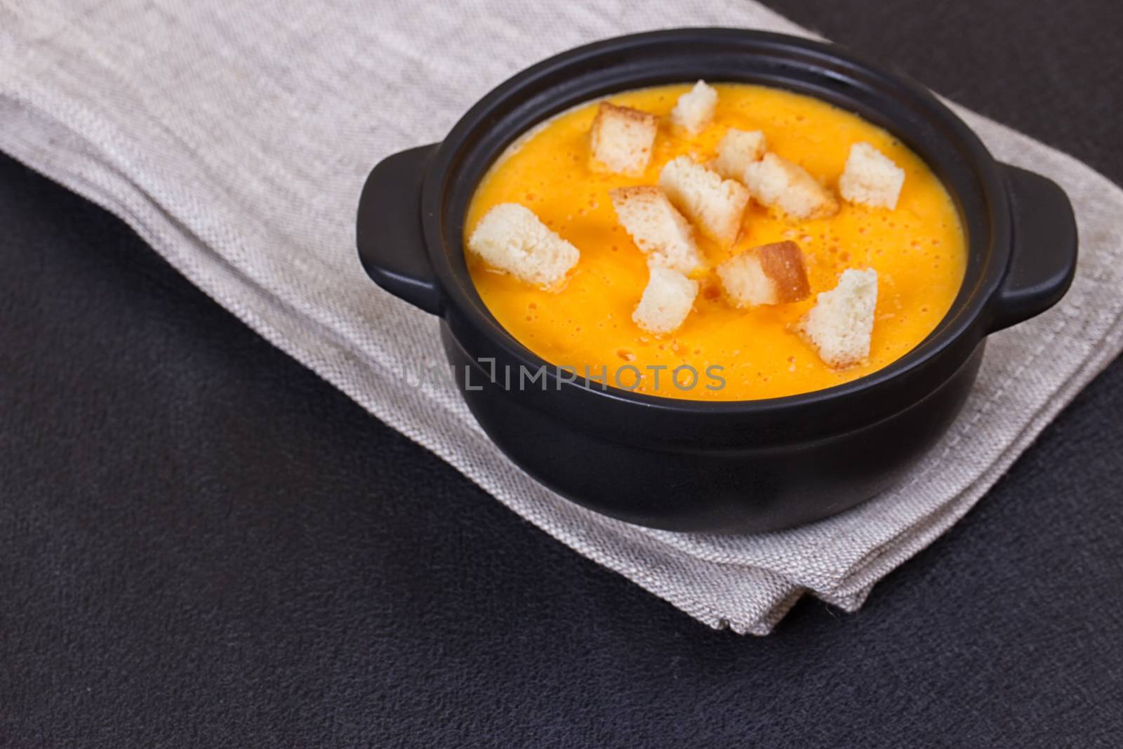 Pumpkin and carrot soup with cream and parsley on dark background Copy space