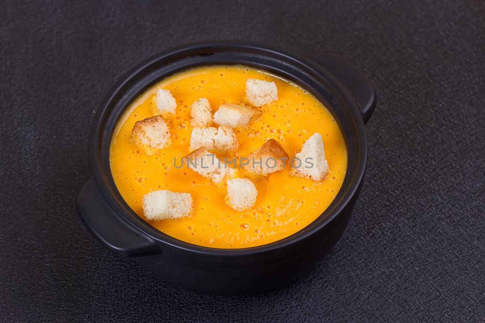 Pumpkin and carrot soup with cream and parsley on dark background Copy space