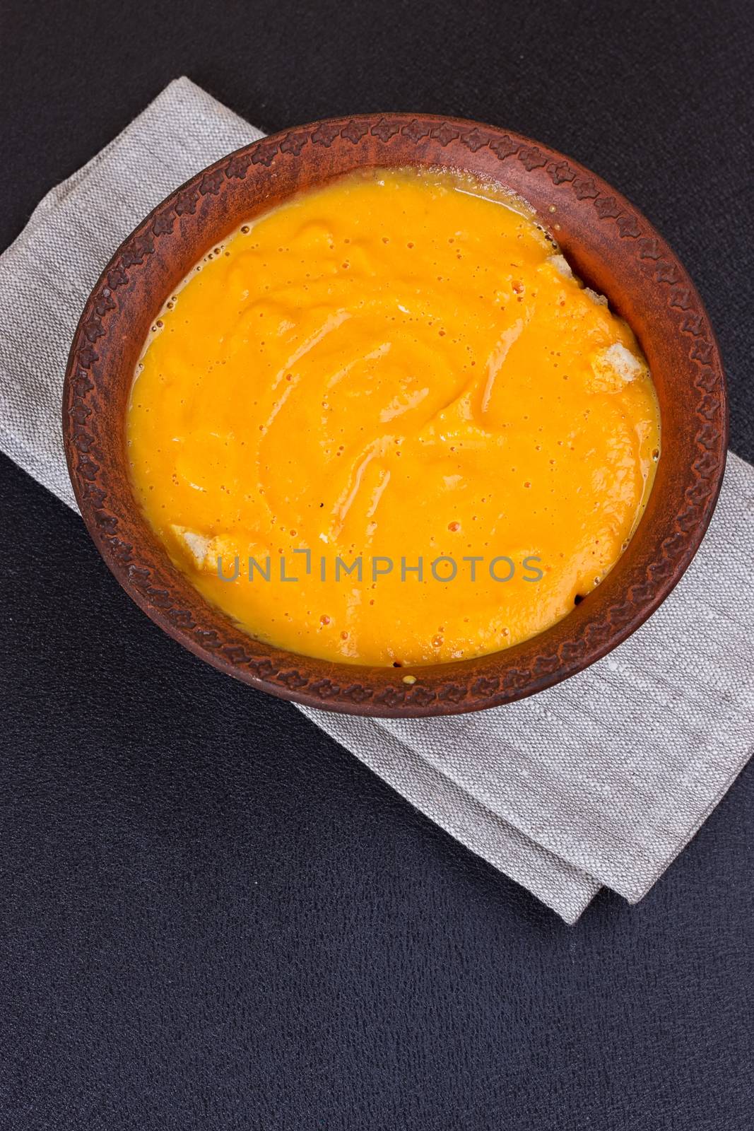 Pumpkin and carrot soup with cream and parsley on dark wooden background Top view Copy space by victosha