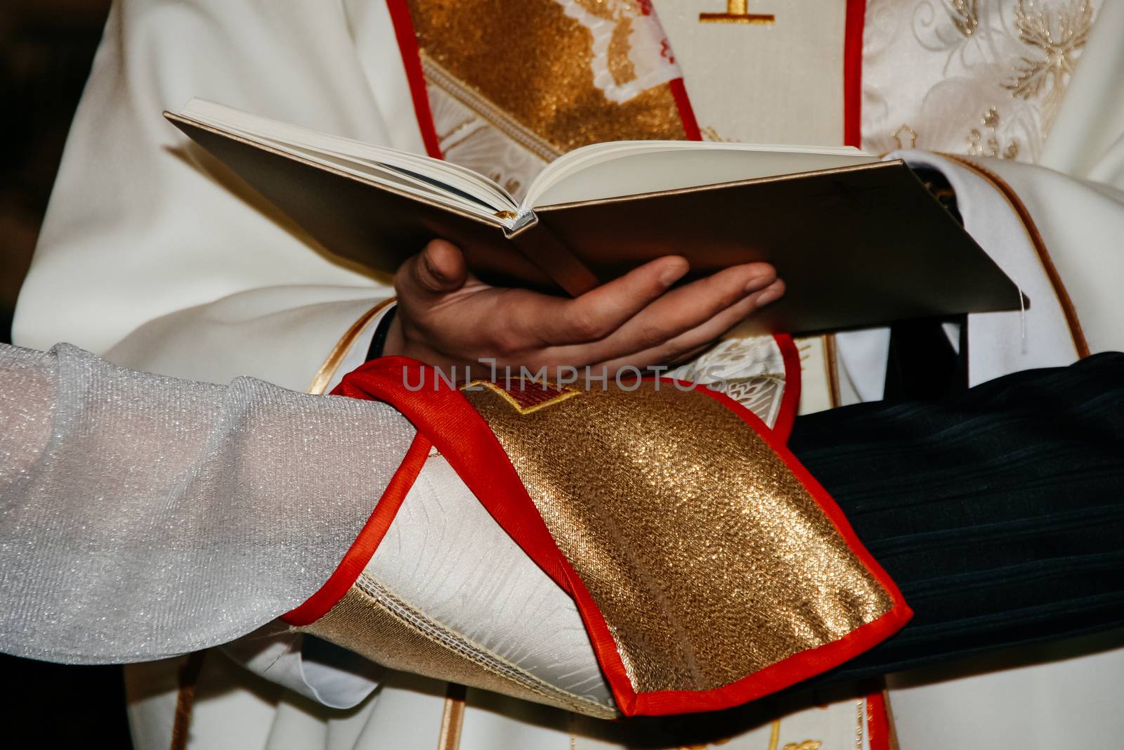 Priest holding bible above hands of bride and groom during wedding ceremony in christian church