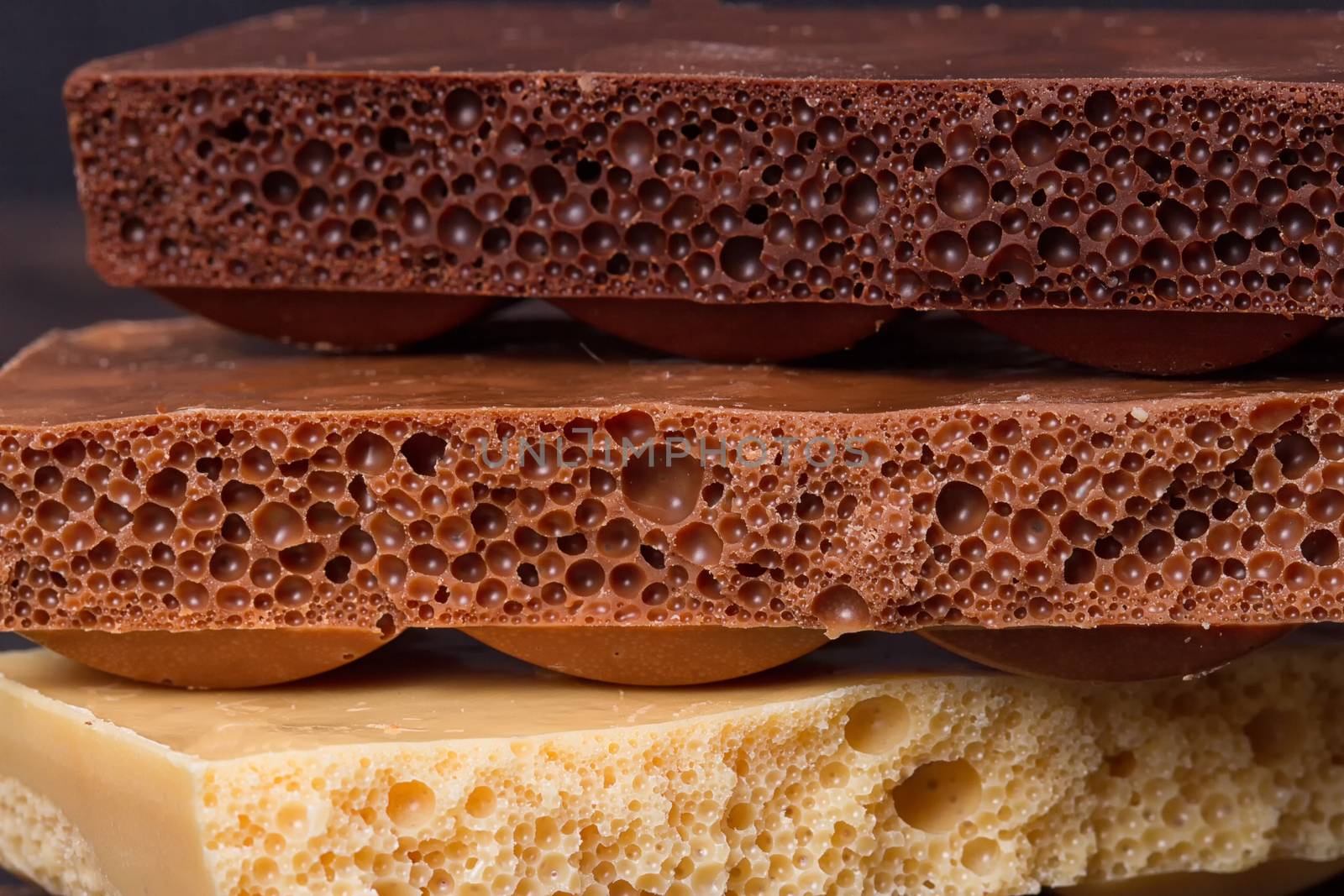 stack of different kind porous chocolate pieces on a dark background.