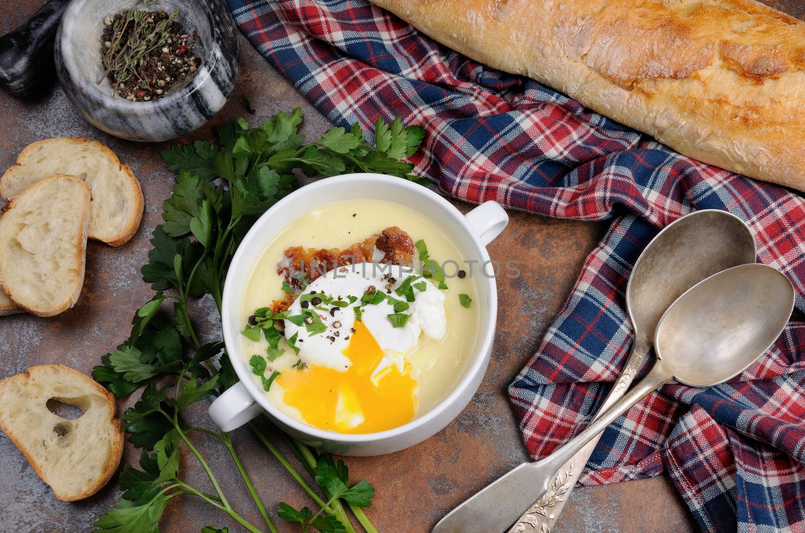 Garlic potato cream soup with bacon and poached eggs, herbs, spices