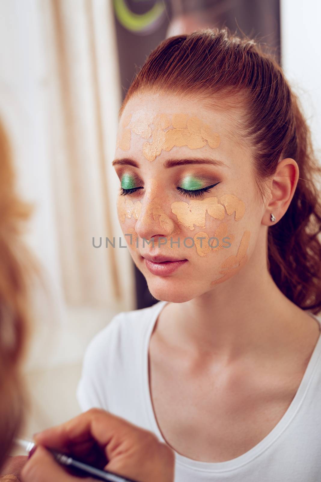 Makeup artist applying powder on a beautiful young woman's face.