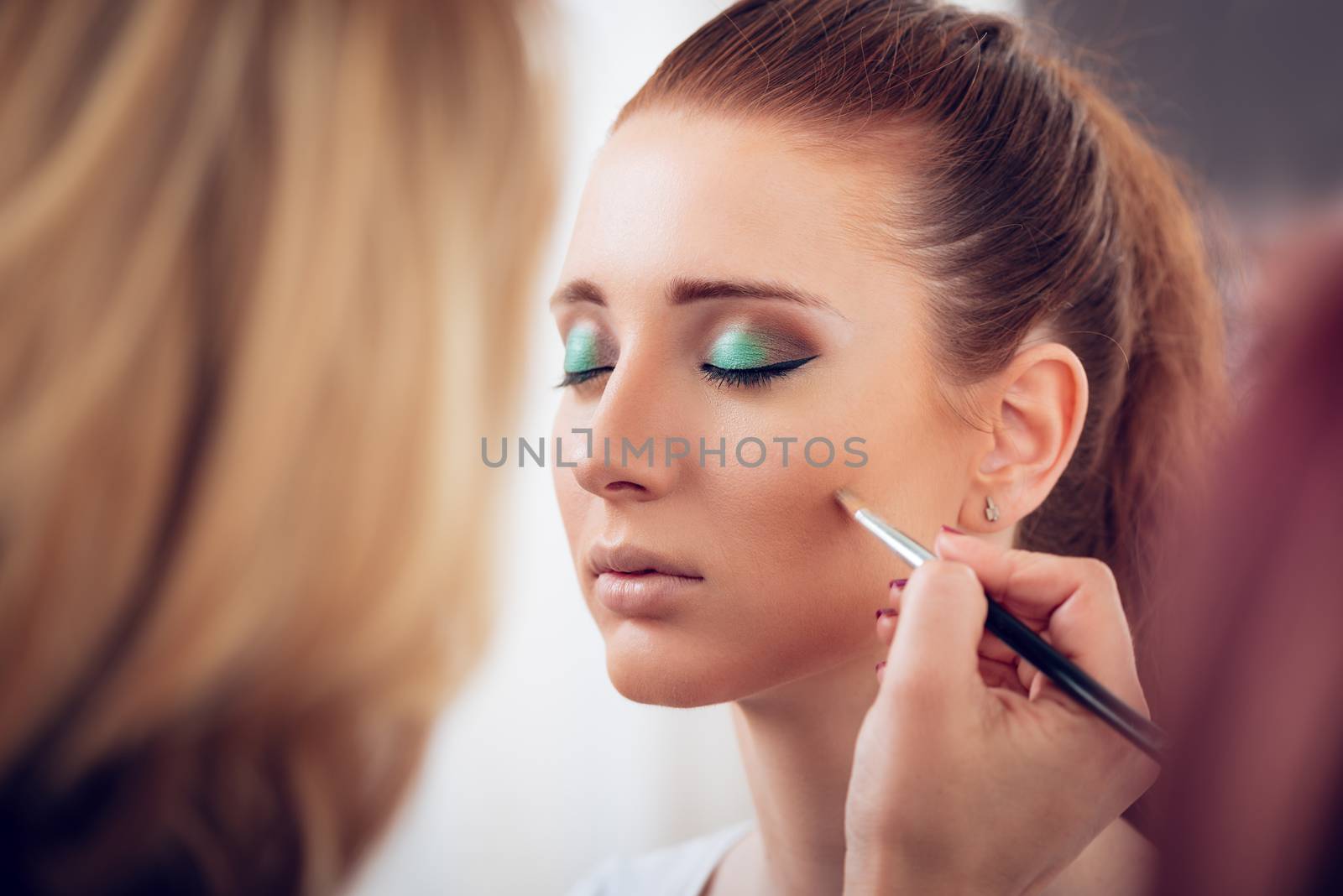 Makeup artist contouring face to model. Close up. 