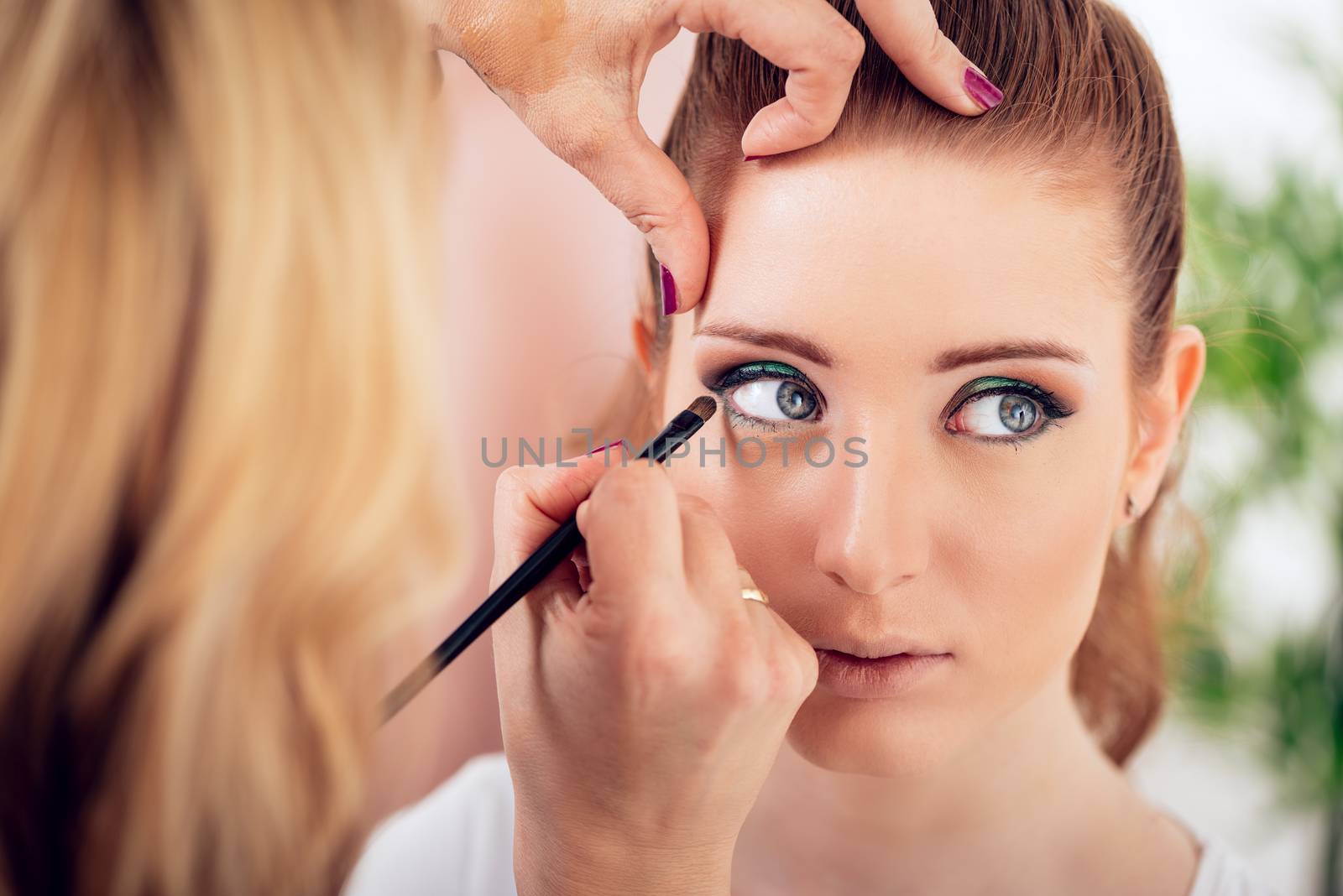 Makeup artist applying the eyeshadow to model. 