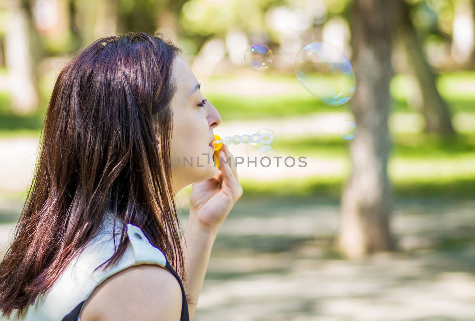 caucasian woman blowing soap bubbles in the park by Desperada