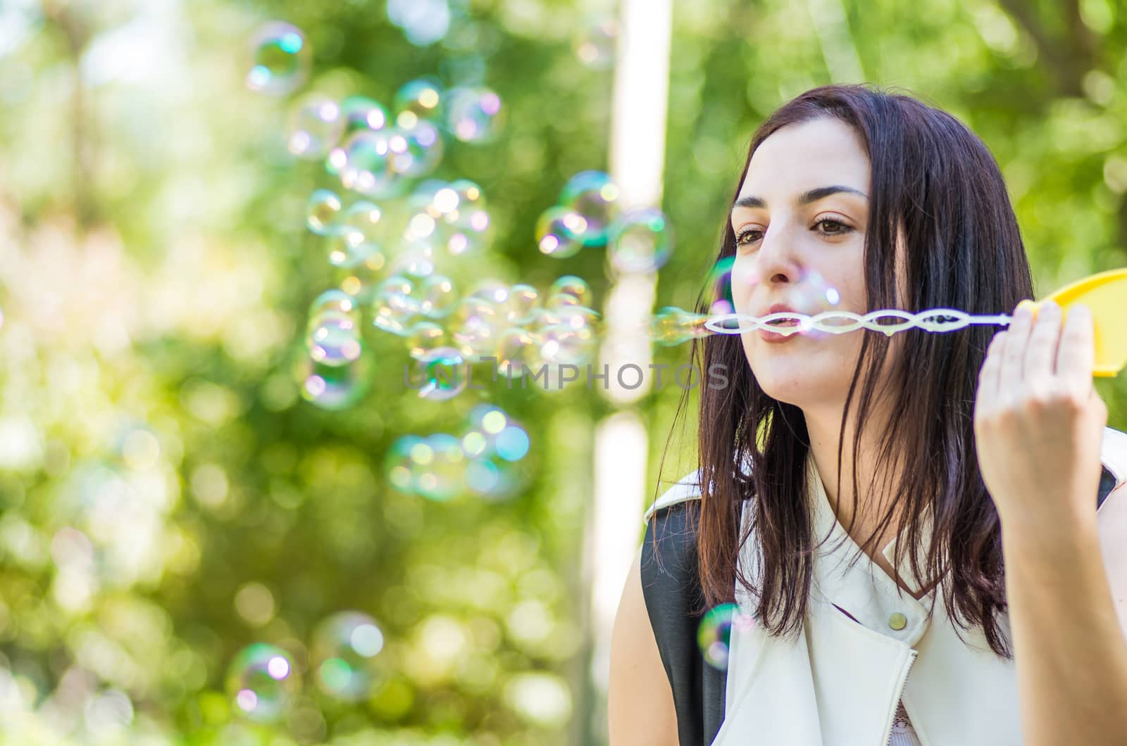 caucasian woman blowing soap bubbles in the park by Desperada