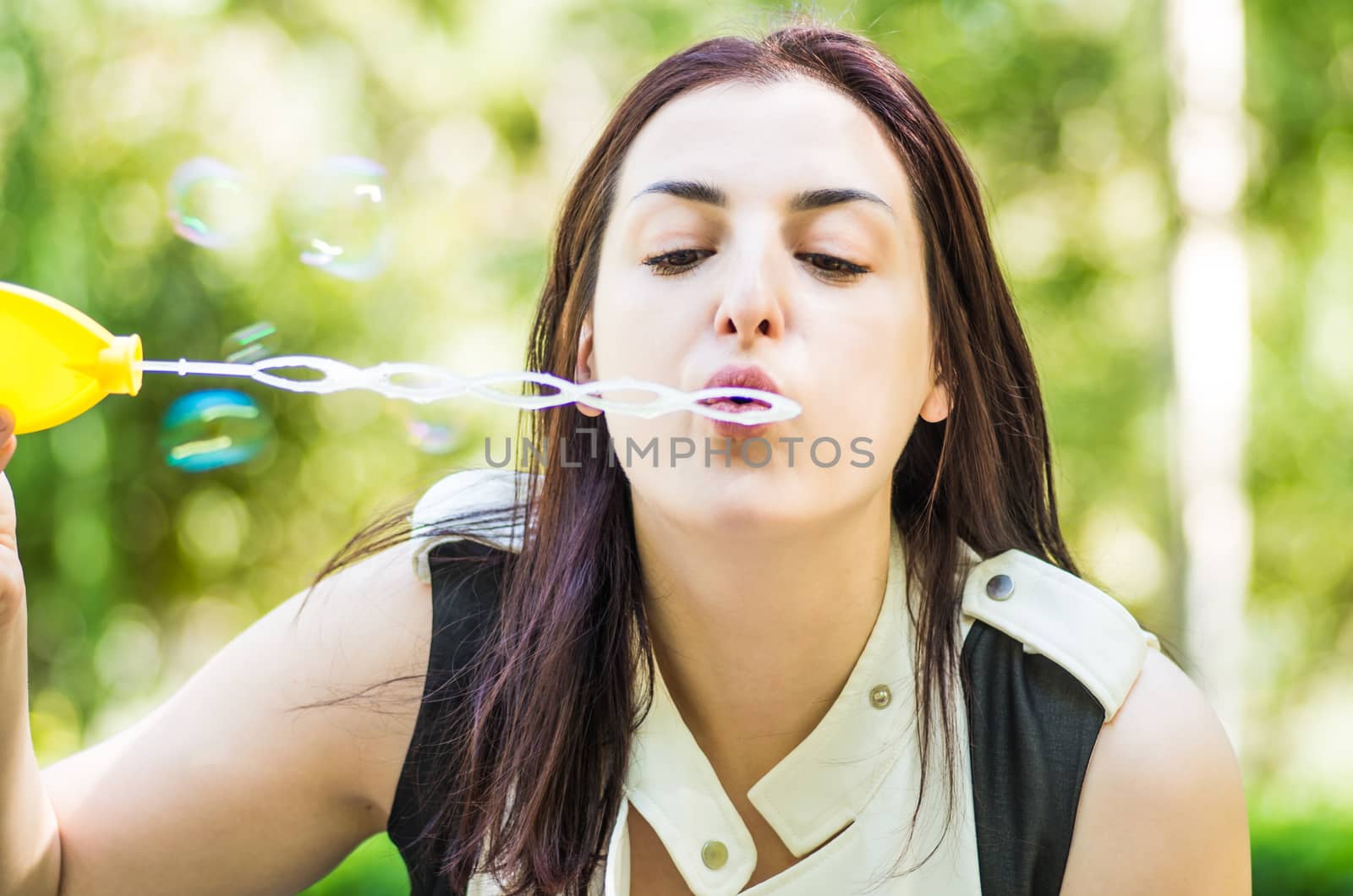 caucasian woman blowing soap bubbles in the park by Desperada