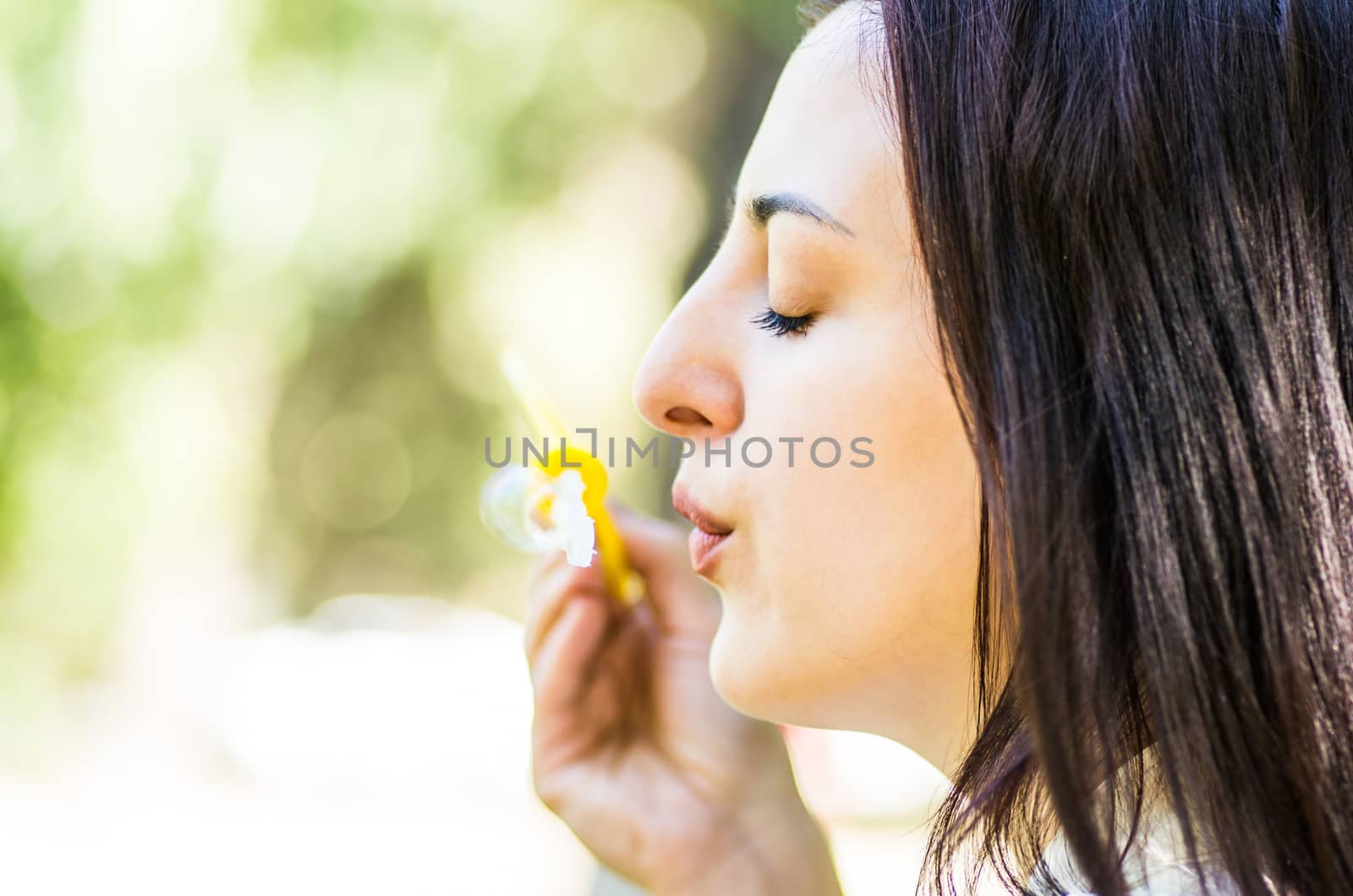 young woman blowing soap bubbles in the park