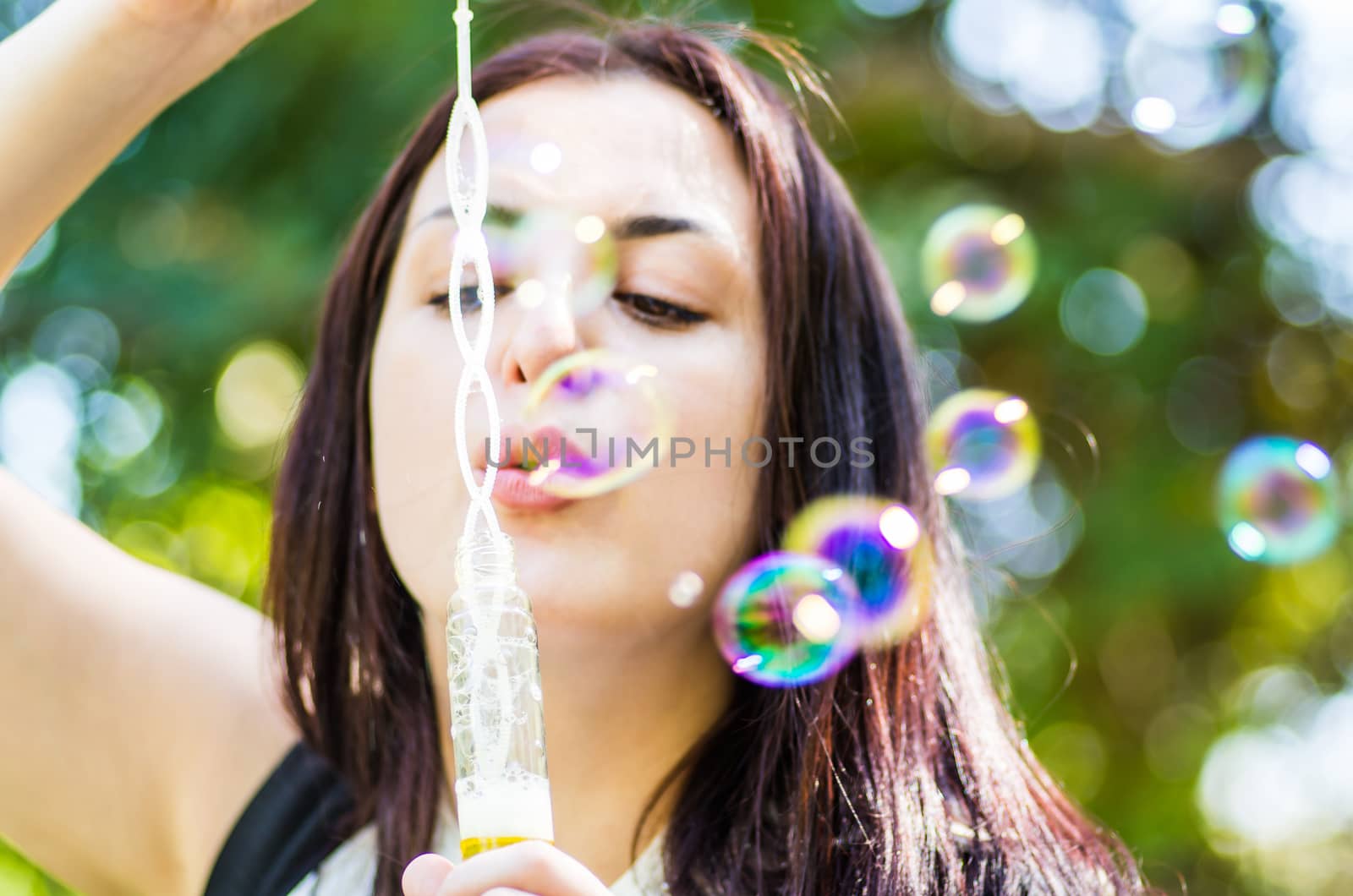 caucasian attractive woman blowing soap bubbles in the park