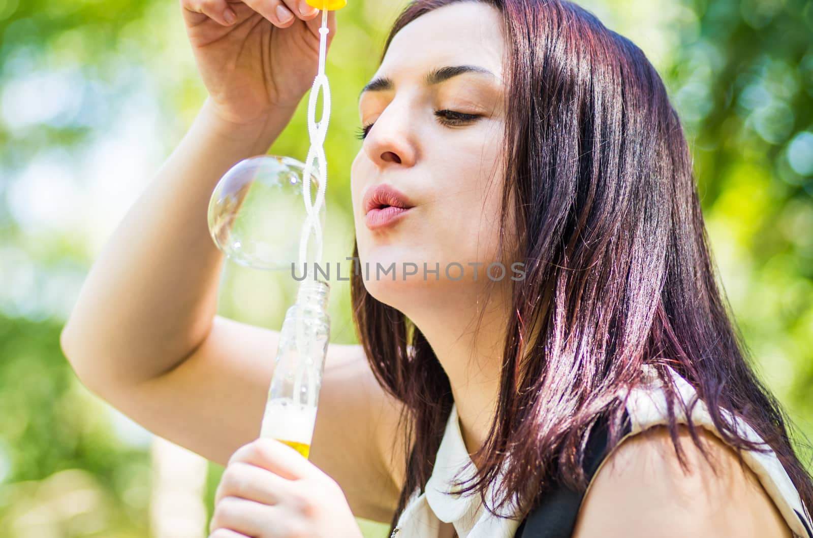 young woman blowing soap bubbles in the park