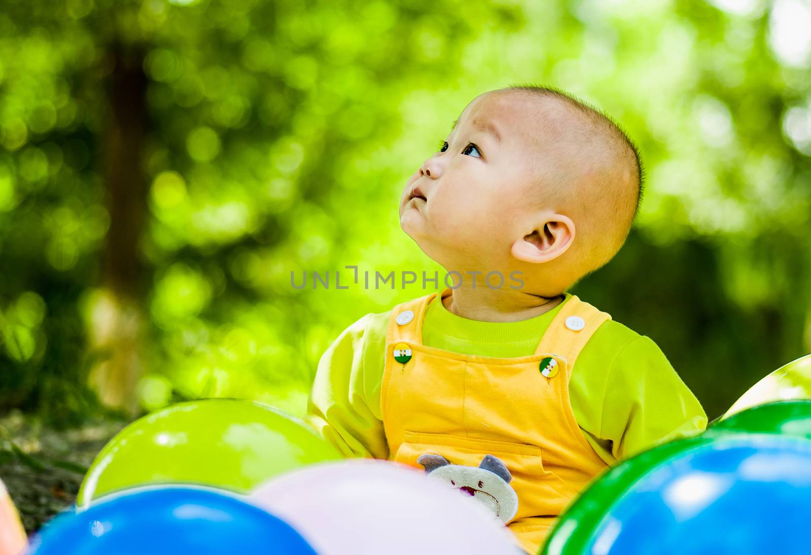 baby sits between balloons looking up