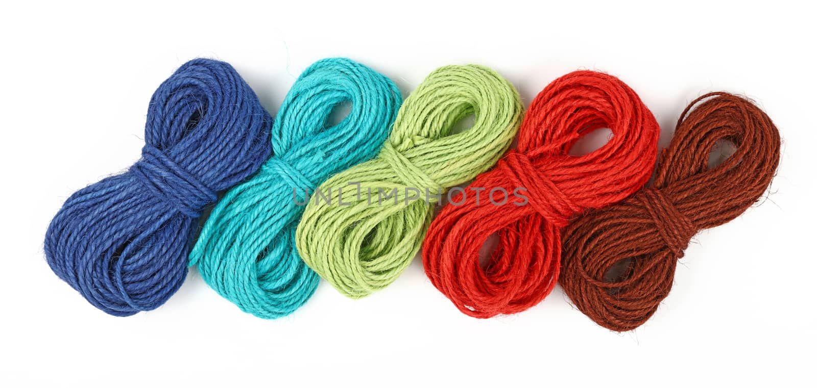 Group of five small coil skeins of natural colorful multicolor jute twine rope, selection of green, blue red, brown and teal, isolated on white background, close up, elevated top view, high angle
