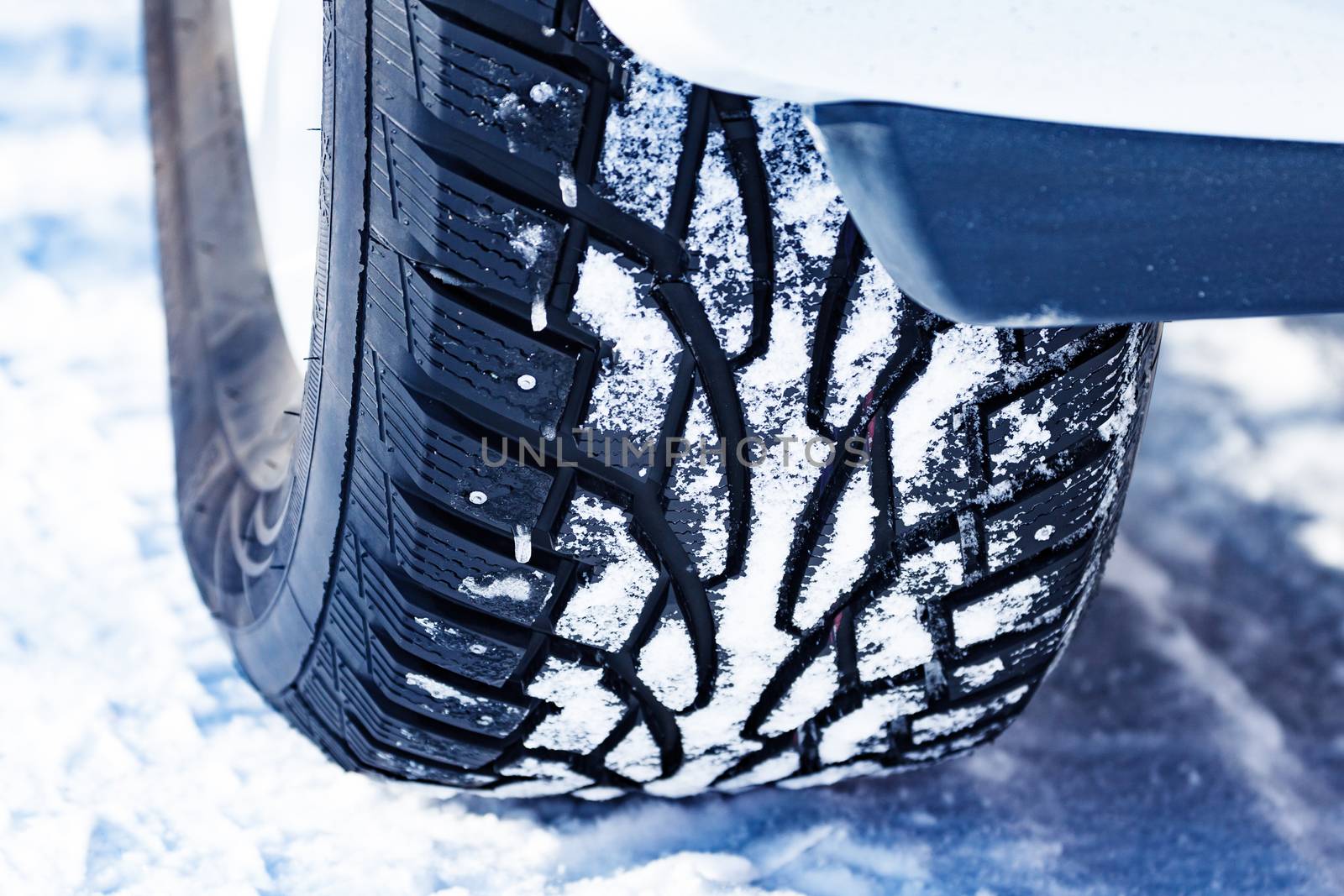 Closeup shot of automobile studded tire covered with snow at winter snowy road