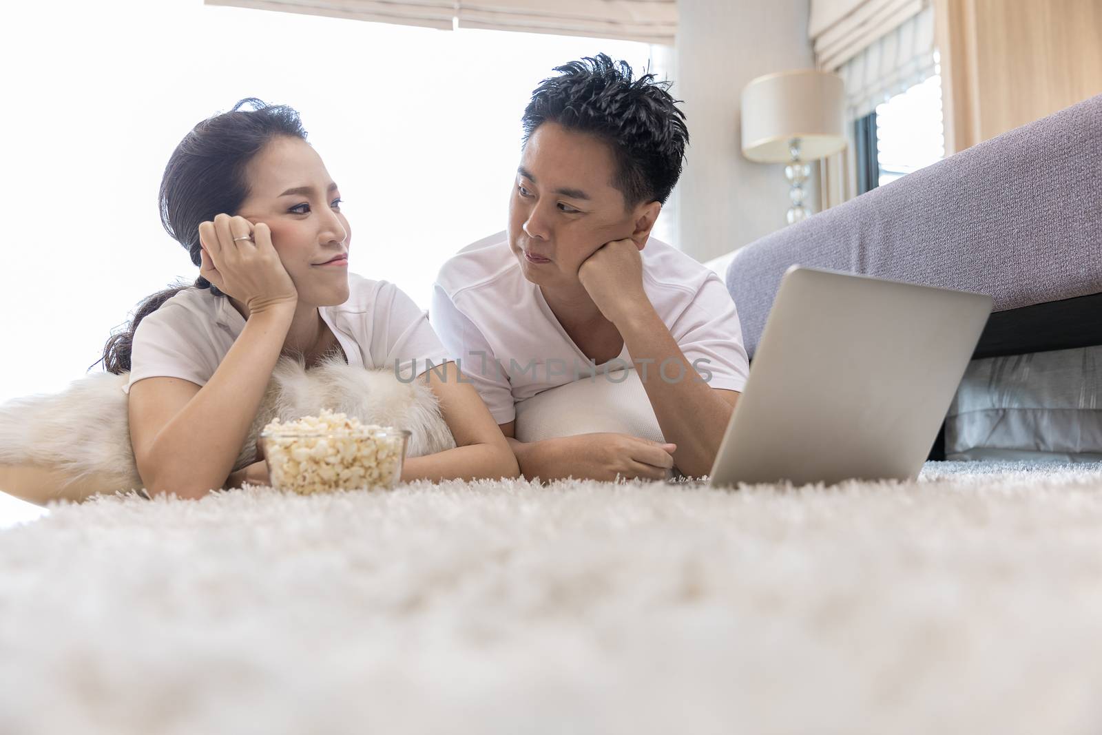 Young Asian Couples using laptop together in bedroom of contemporary house for modern lifestyle concept