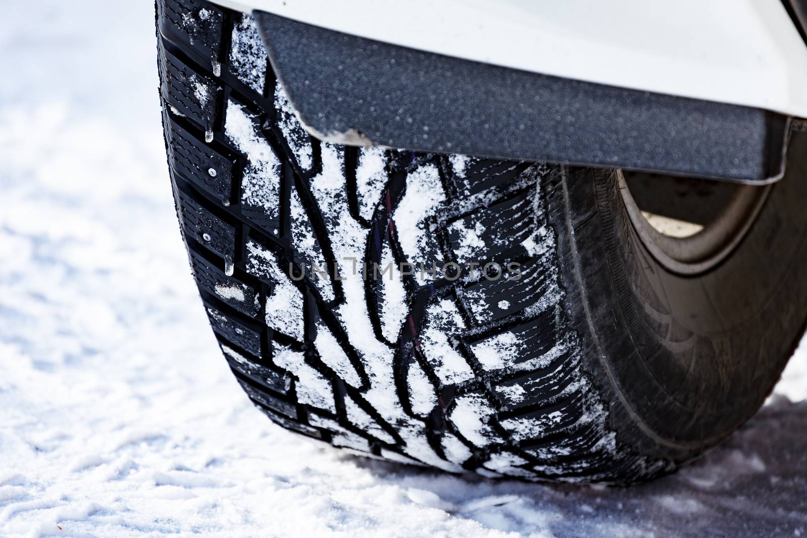 Closeup shot of automobile studded tire covered with snow at winter snowy road