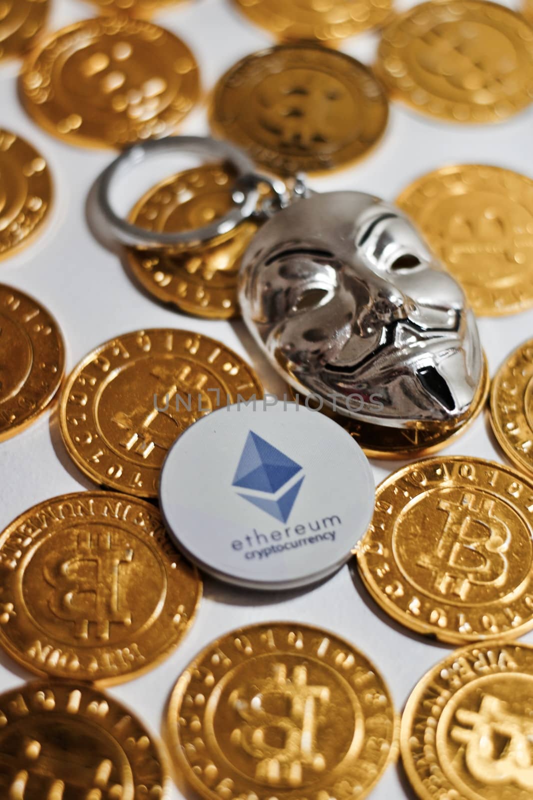 Digital currency physical grey Ethereum coin near gold bitcoins.