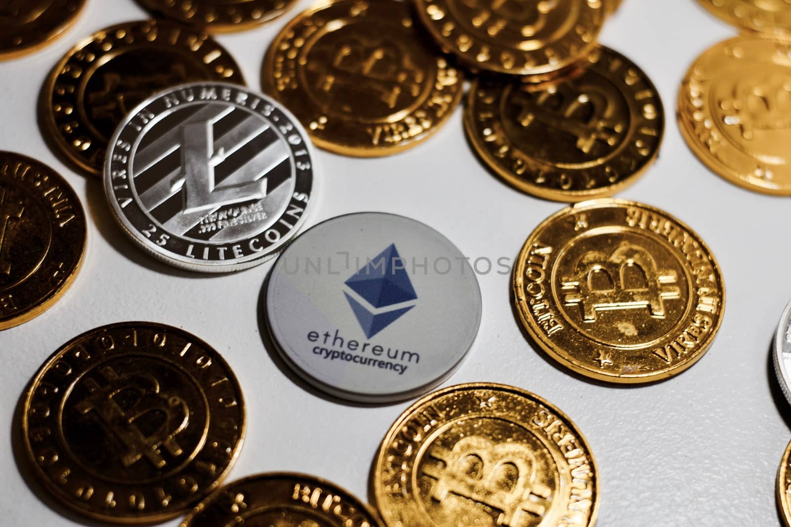 Digital currency physical grey Ethereum coin near gold bitcoins.