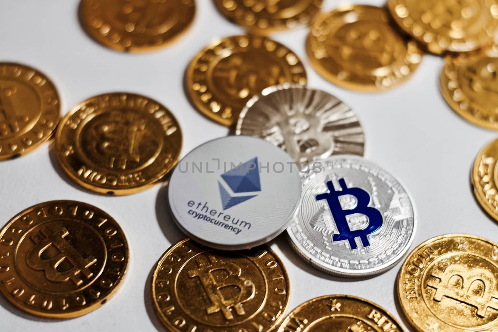 Digital currency physical grey Ethereum coin near gold bitcoins.