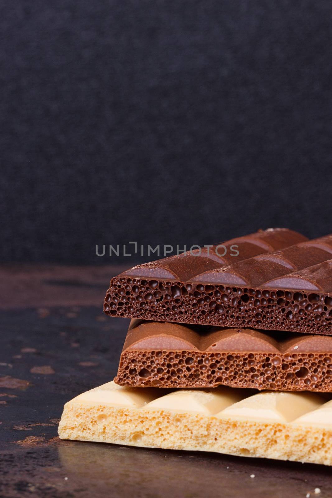 milk, dark and white chocolate bars on grunge background