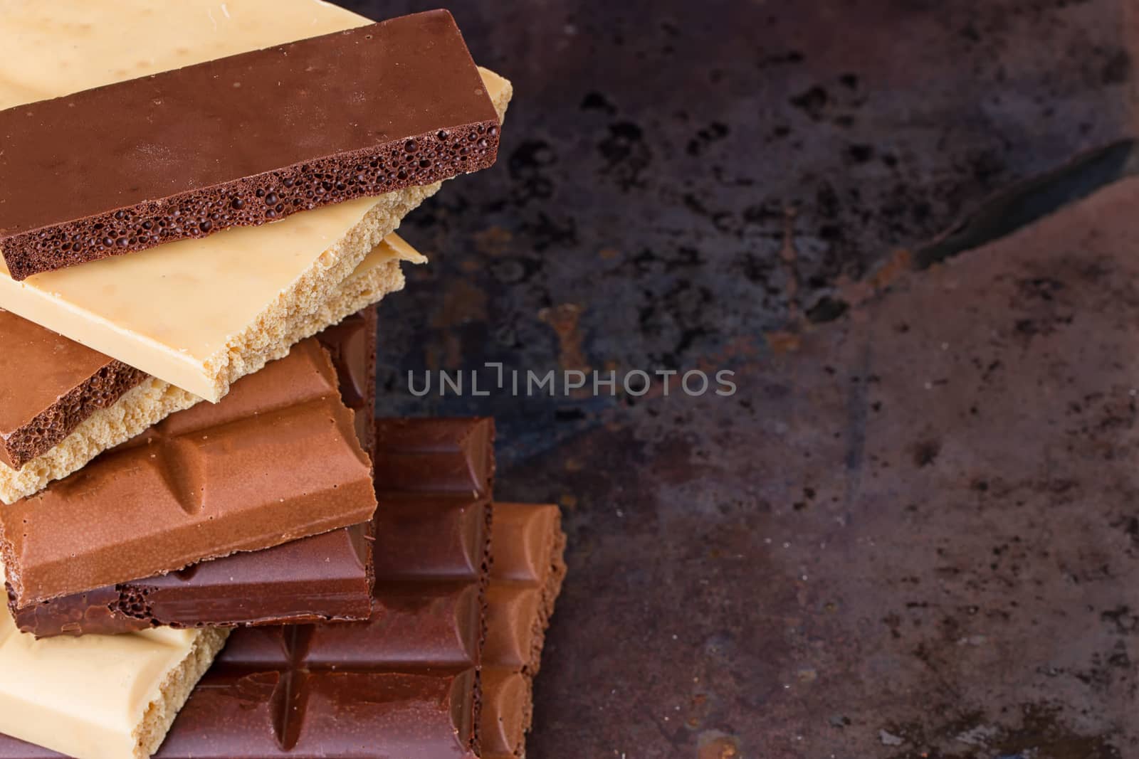 milk, dark and white chocolate bars on grunge background