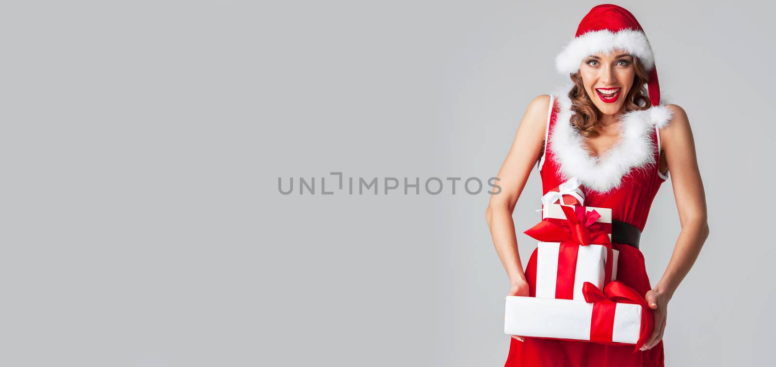 Beautiful woman in Santa Claus style dress with gift boxes