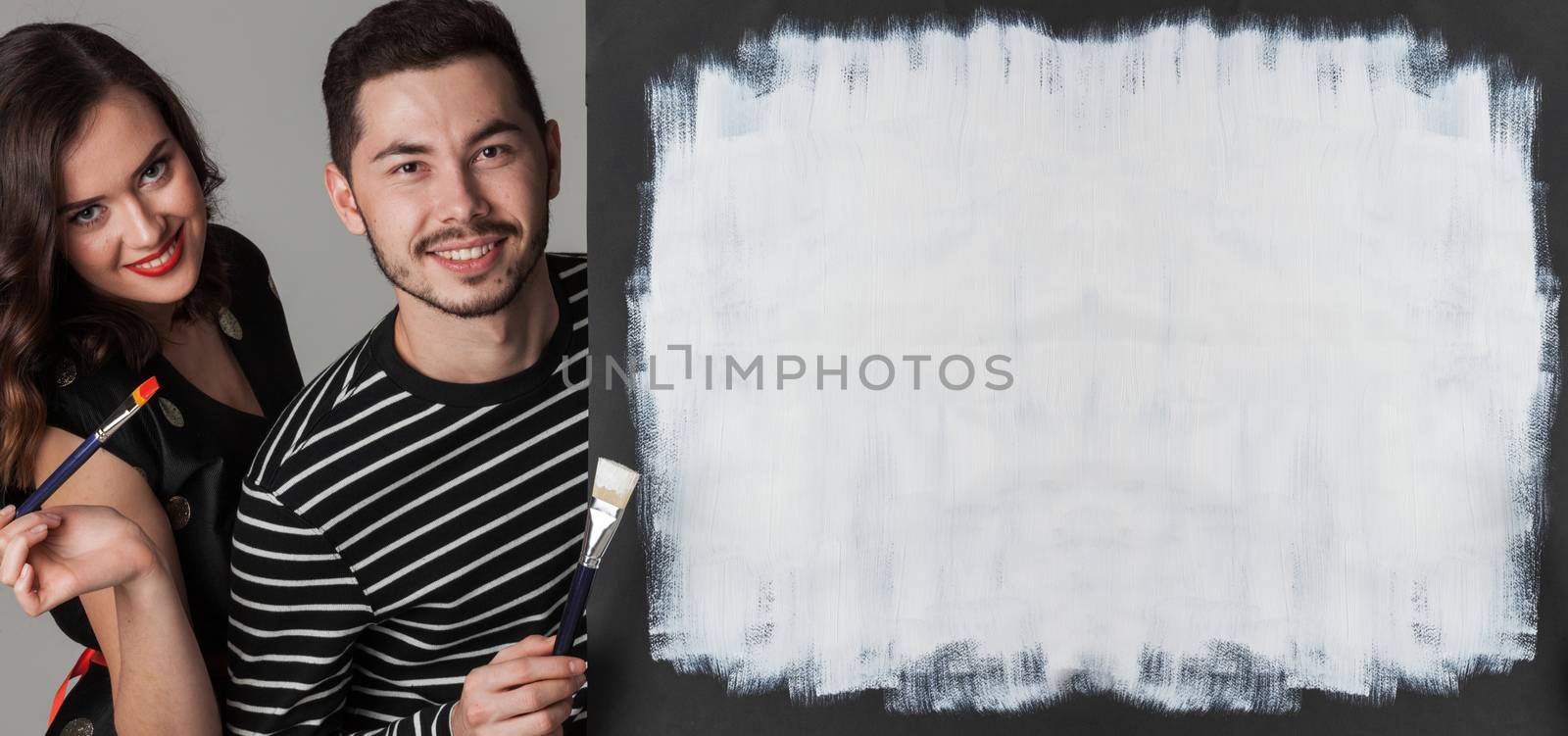 Couple with paint brushes and picture with white blank copy space