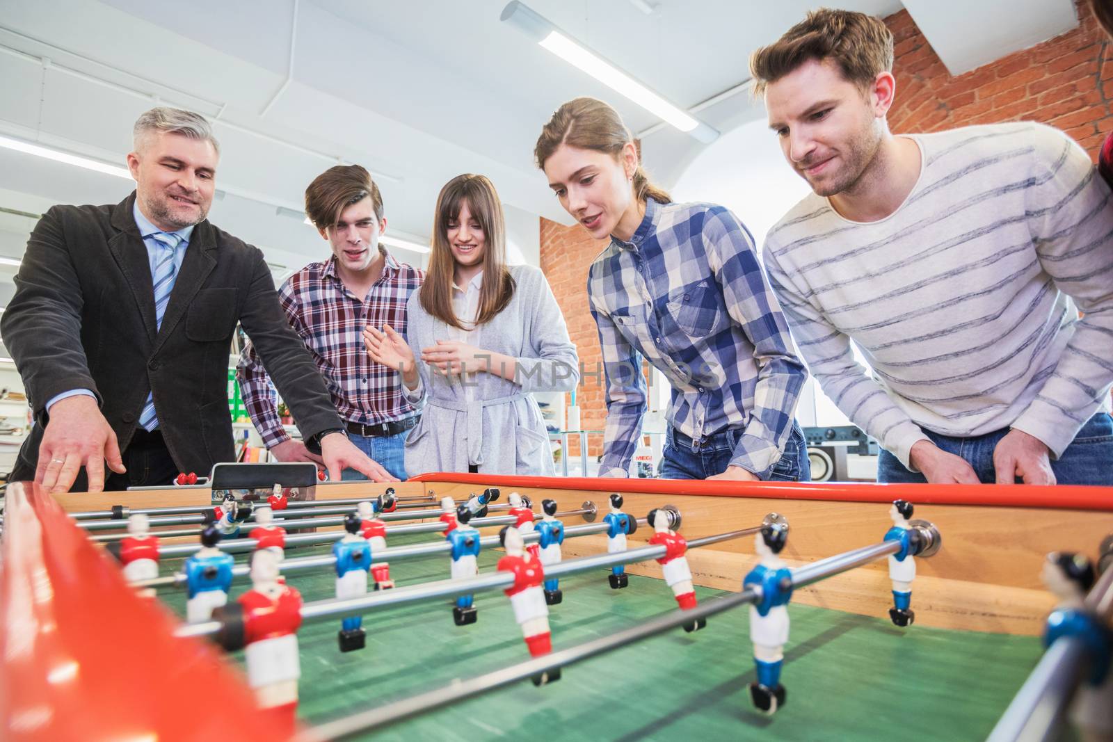 Group of happy people playing table soccer together