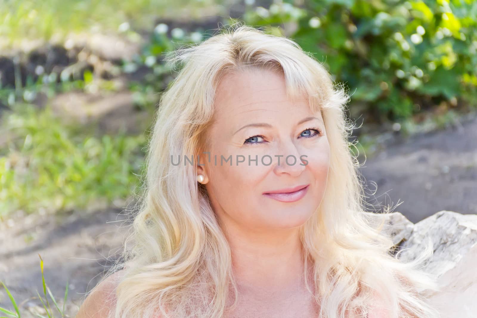 Portrait of blond woman with sapphirine eyes in summer