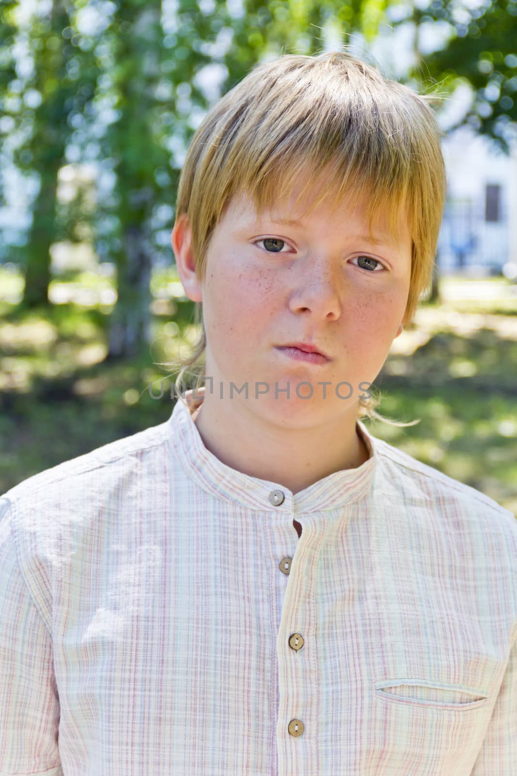 Portrait of serious boy in park by Julialine