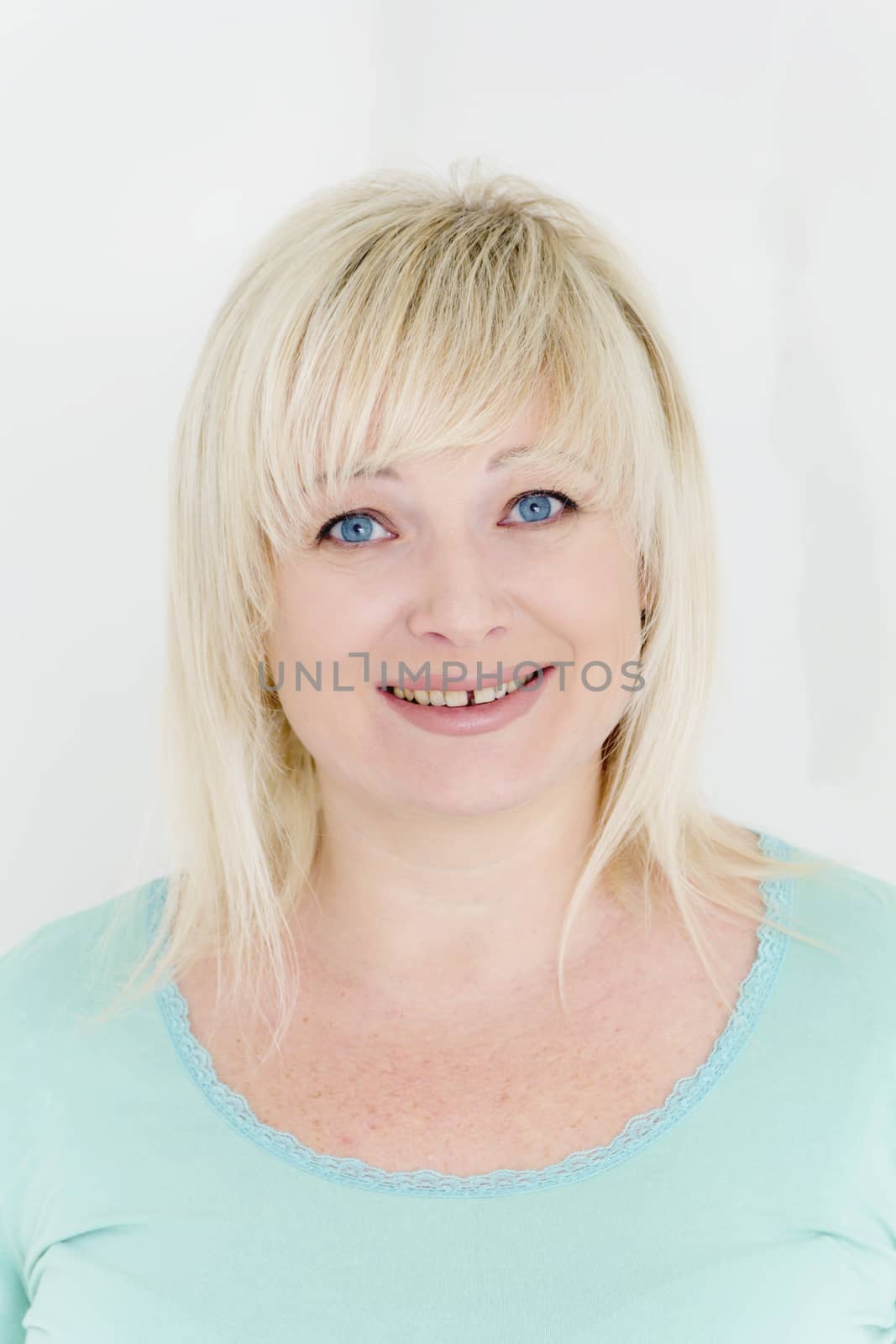 vertical portrait of blond woman with blue eyes in green