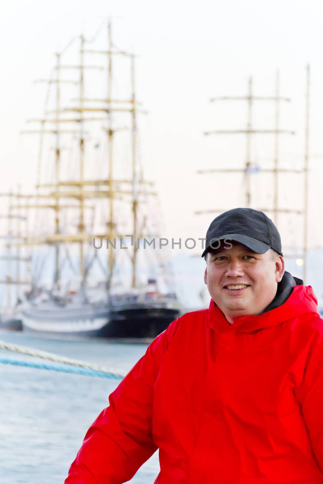 Big fat man in red jacket on ship background