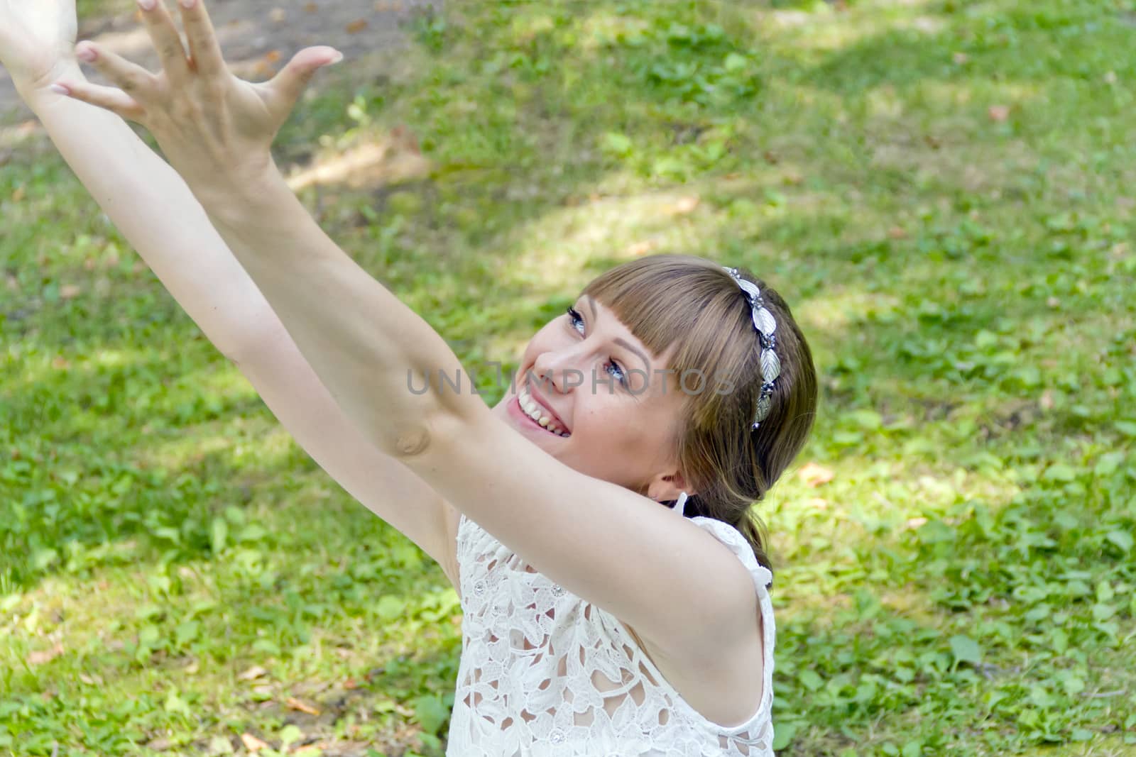 Smiling bride in white lace dress with upwards hands