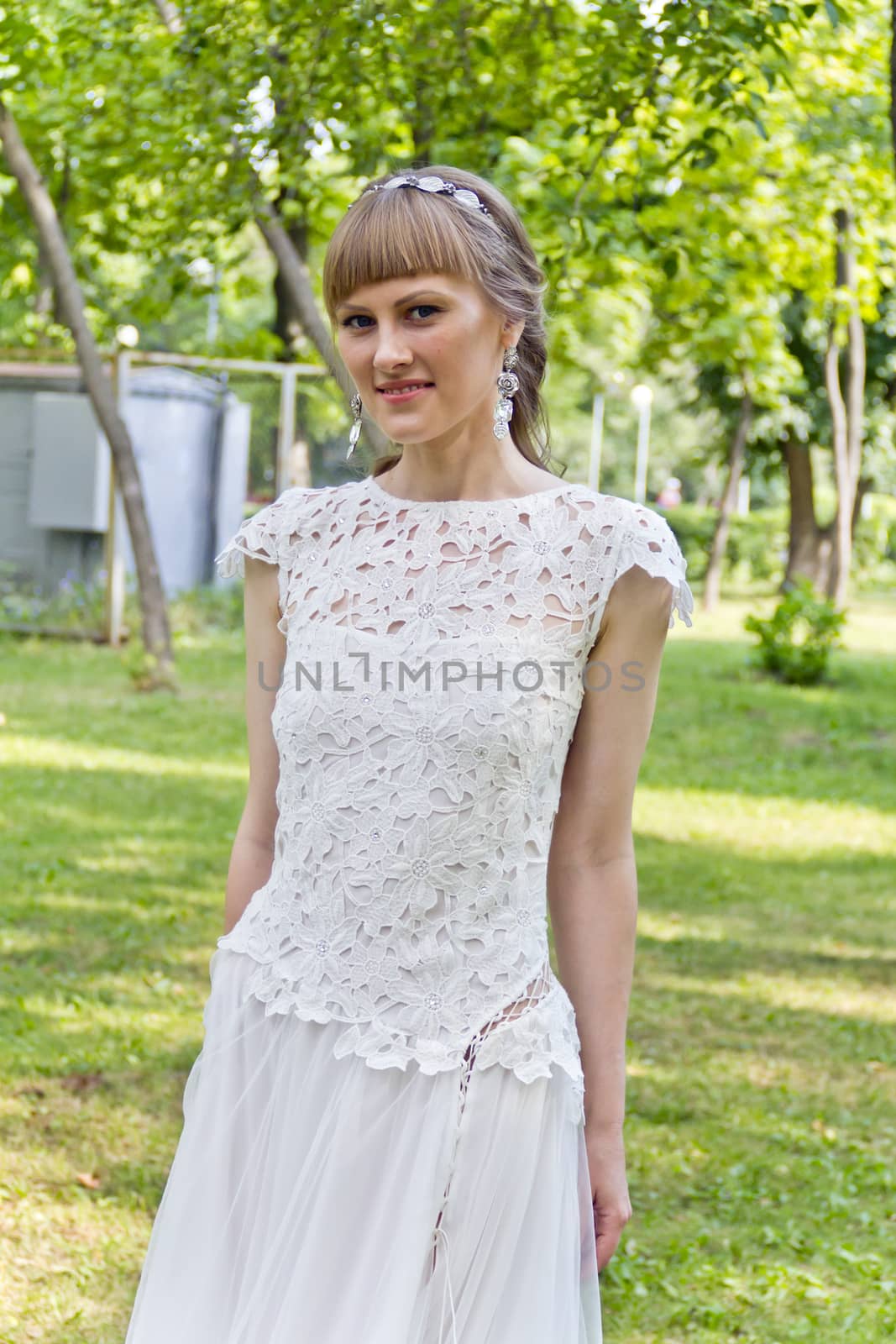 Beautiful bride in white lace dress of the summer park