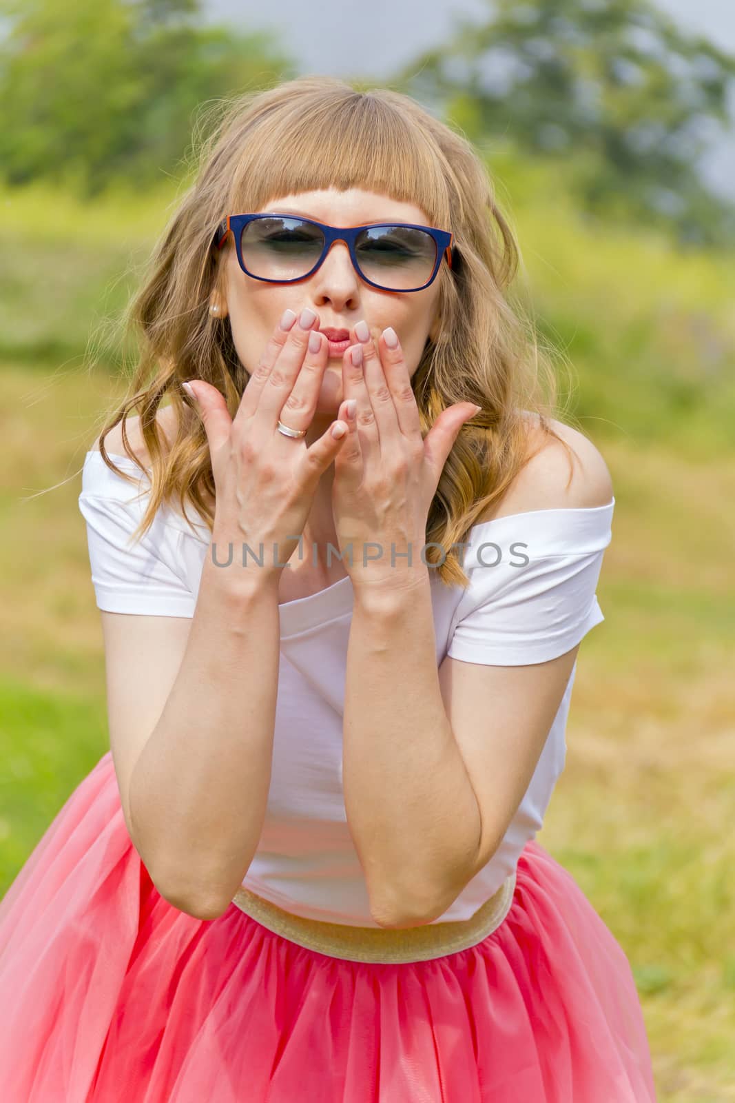 Young girl in sunglasses and pink skirt sending air kiss