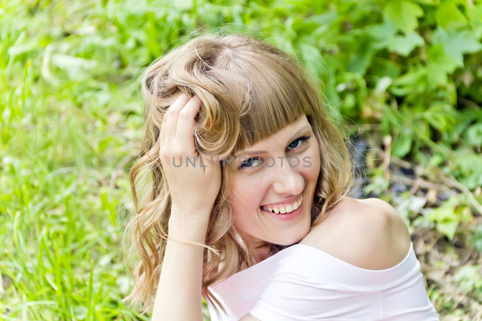 Portrait of beautiful girl straightening her hair on green background