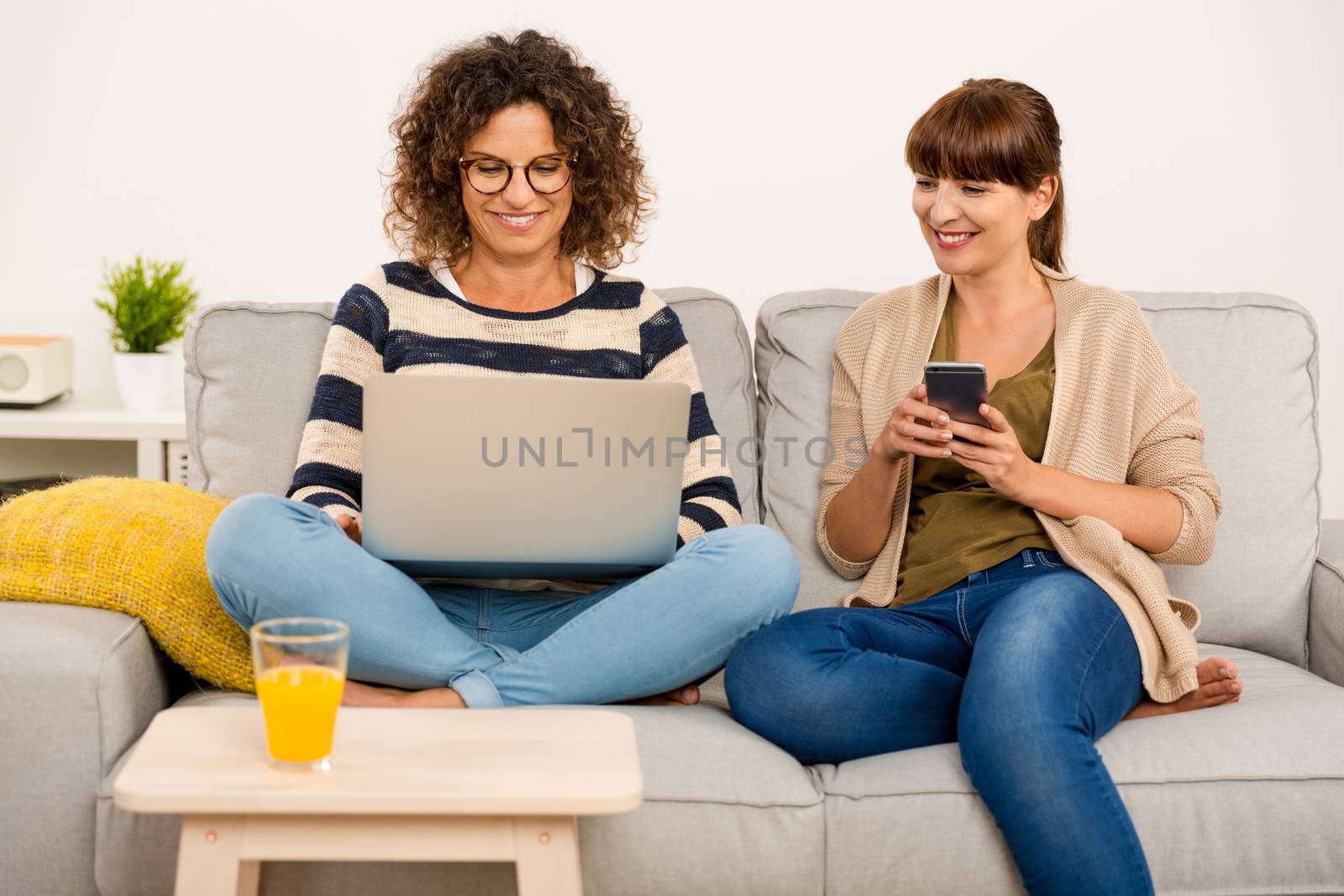 Two beautiful women at home working with a laptop