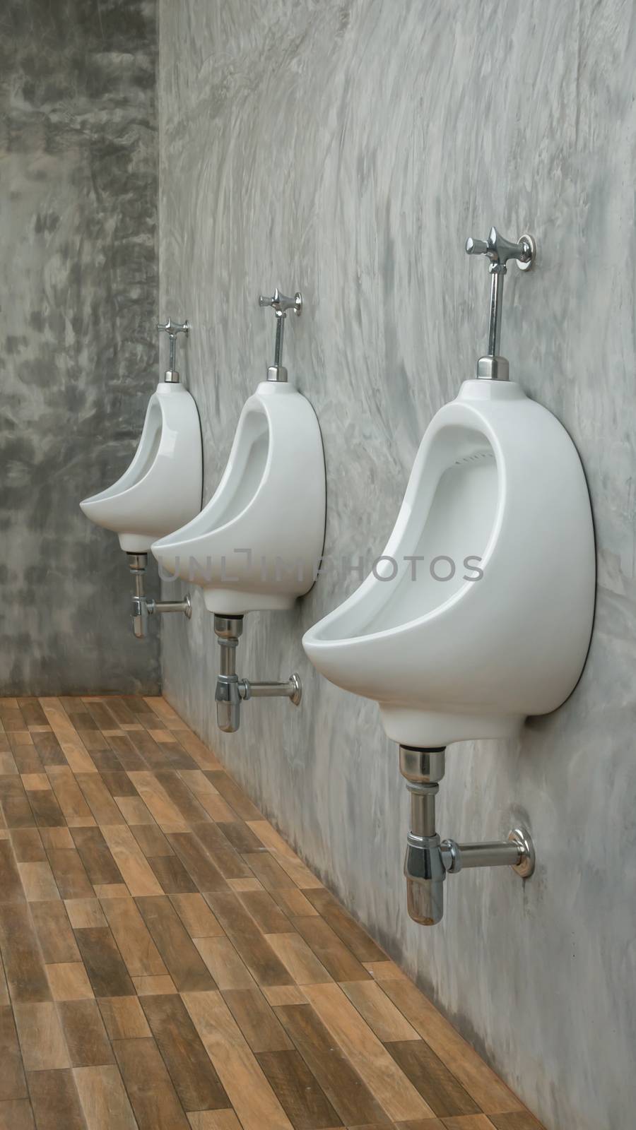 three white urinals men public toilet in restroom outdoors