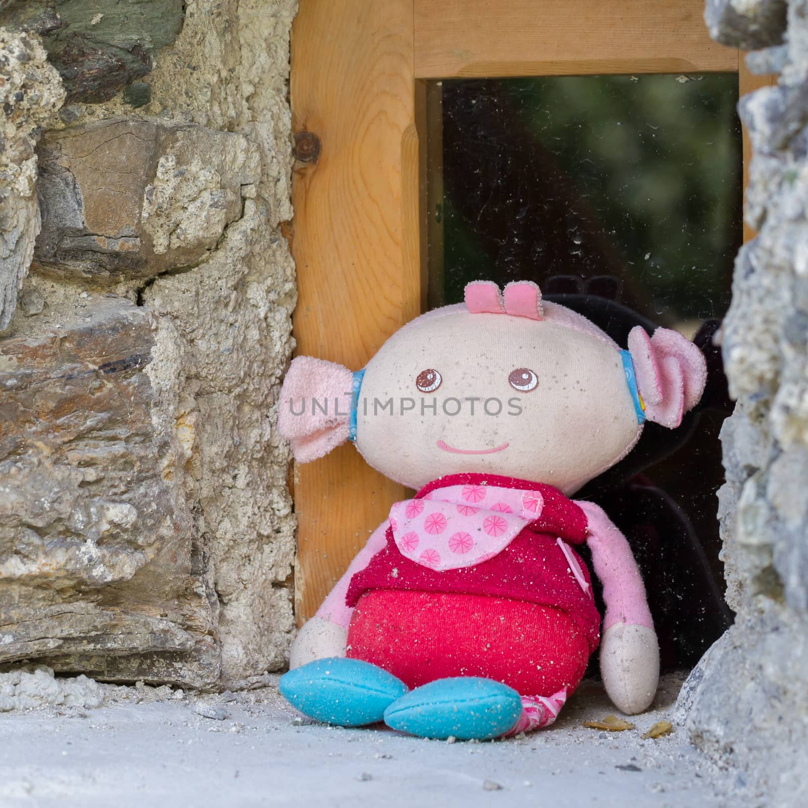 Old stuffed doll sitting in front of a window